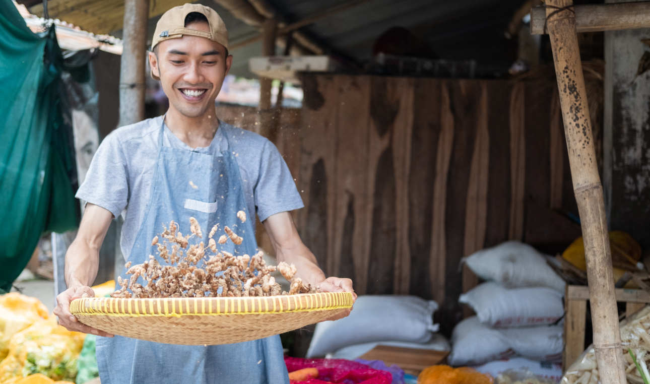 male merchant holding woven tray containing turmeric